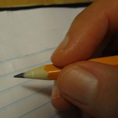 hand holding pencil while writing